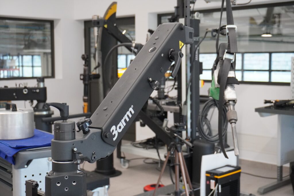 Opérateur utilisant un bras articulé industriel équipé d'un équilibreur de charge dans un atelier de fabrication